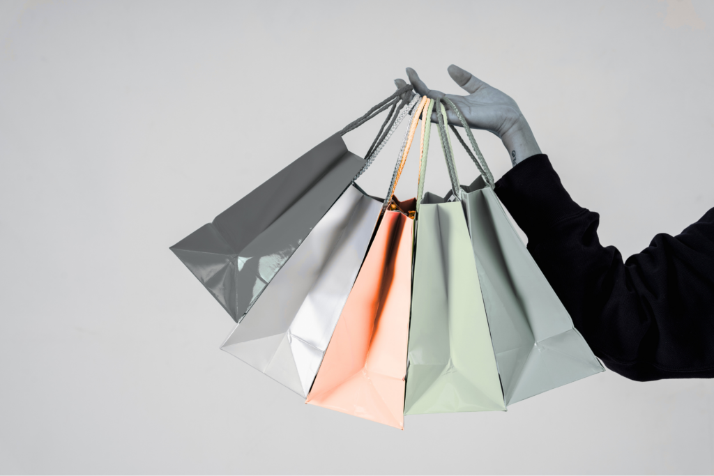 Hand mit mehreren eleganten Einkaufstüten – stilvolles Shoppingkonzept, Einzelhandel, Konsumverhalten und moderne Kundenbindung.