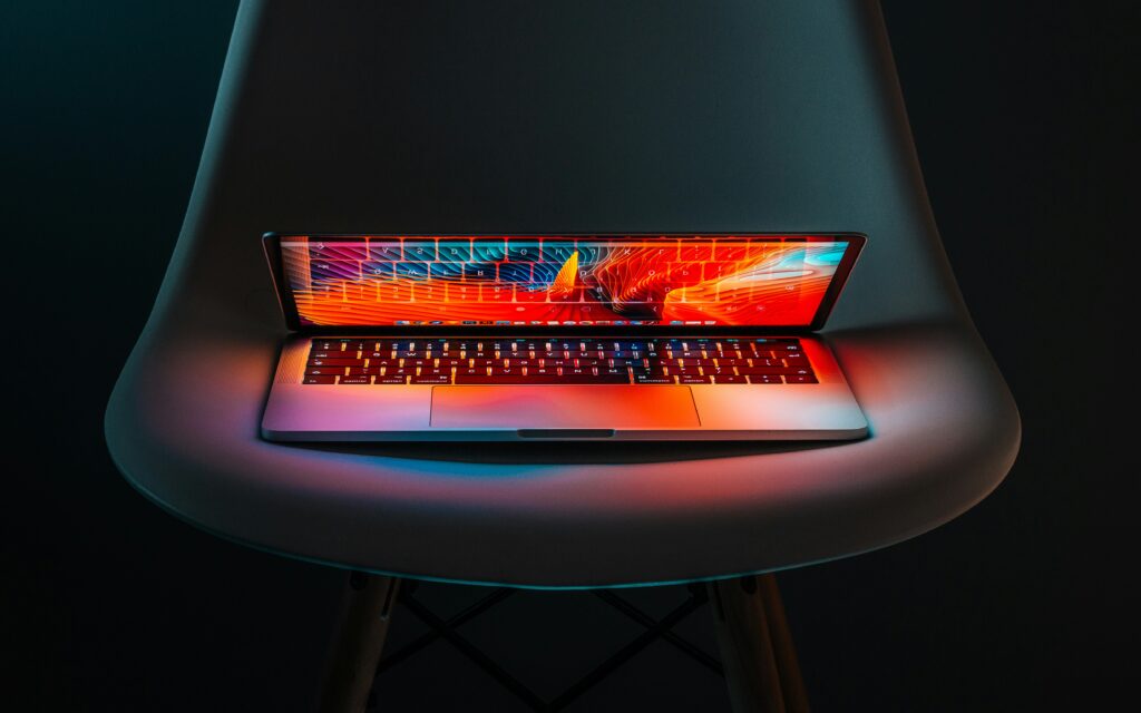Teilweise geschlossener Laptop auf Stuhl mit leuchtendem Bildschirm