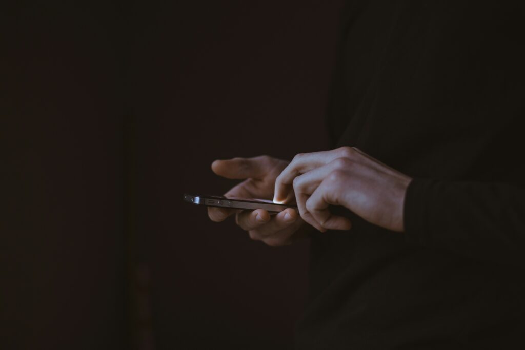 Person tippt auf Smartphone in dunkler Umgebung