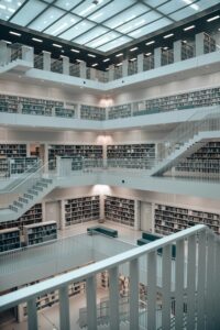 Zentrale Perspektive einer futuristischen Bibliothek mit symmetrischen Treppen, Regalen und Lichtdecke